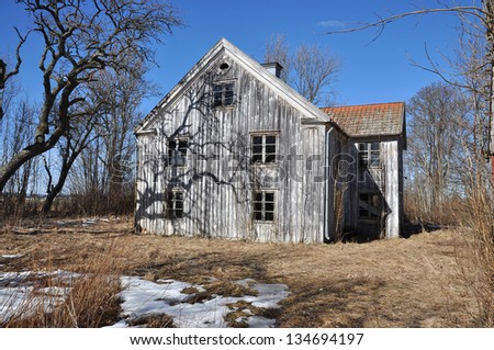 Old dilapidated wooden house with scary shadows and trees