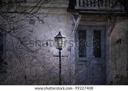 Vintage lamppost in front of a dilapidated old house with a blue door.