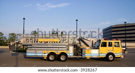This is a side view of a fire truck with ladders and a bucket used for reaching fires in high places.