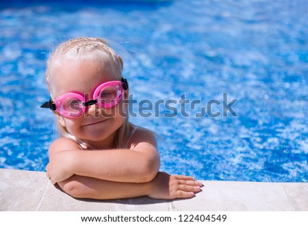 Smiling baby girl  wearing swimming glasses in swimming pool