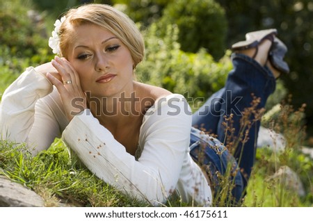 Young woman lying in the grass on a hot spring day, day dreaming about something.
