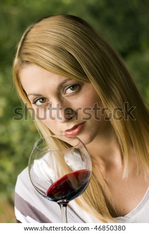 Portrait of the beautiful young woman holding a glass of red wine.