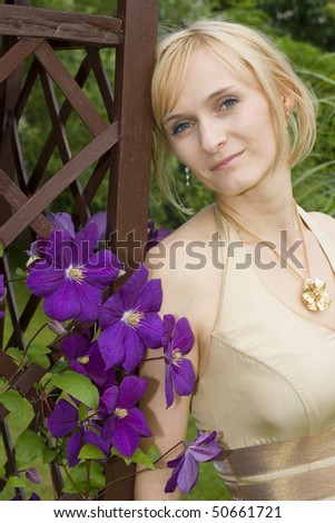Woman in golden wedding dress posing in the garden by the purple flowers.