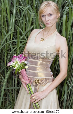 Woman in golden dress with wedding bouquet.