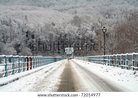 Snow on the iron bridge with forest in the background.