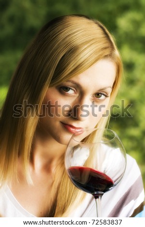 Young woman holding a glass of red wine. Lipstick marks on the glass.