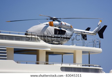 Covered silver helicopter on the deck of the yacht.
