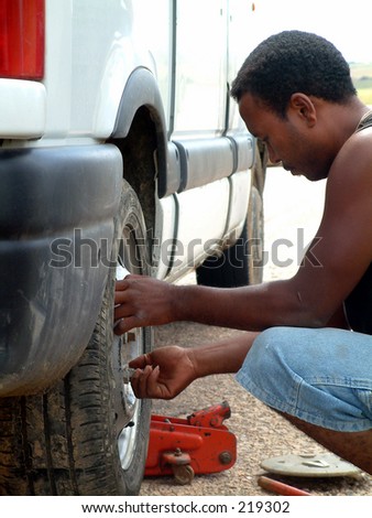 Driver of taxi-brousse changing a flat tire,Madagascar 2004.