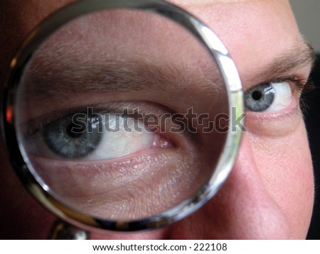 man looking through magnifying glass.