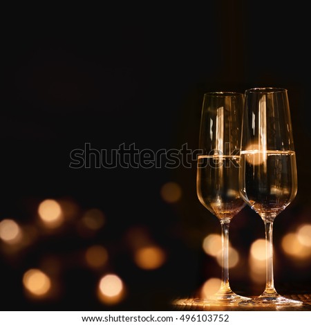 Champagne glasses for festive occasion against a dark background with lights
