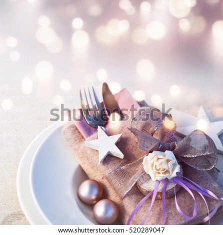 Christmas table decoration in silver and pink in front of a festive background with bokeh