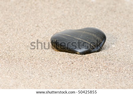 Black stone heart in sand