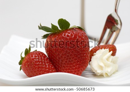 Red fresh strawberries with dessert fork and whipped cream