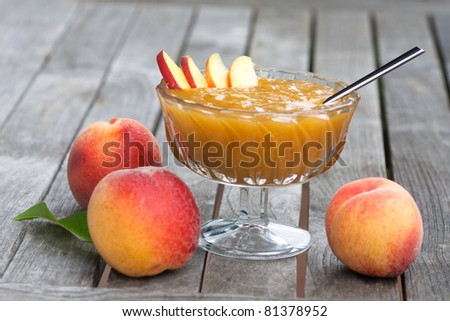Peach jam in a glass bowl and fresh peaches