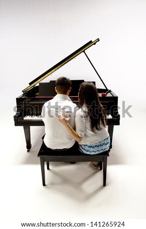 Couple with Grand piano 1 in white shirt, black pants and sundress sitting at piano bench with red rose.