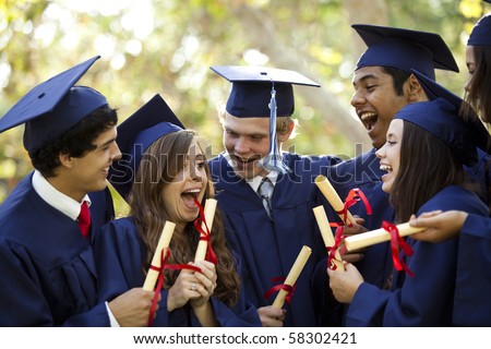 Graduating students smiling and laughing with diplomas; trees in background
