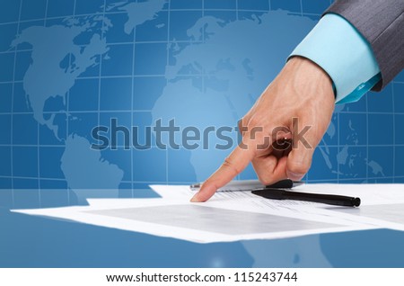 business man hand in elegant suit point finger at the document, paper on the desk over digital globe map background, sign up contract Concept of global international business collaboration