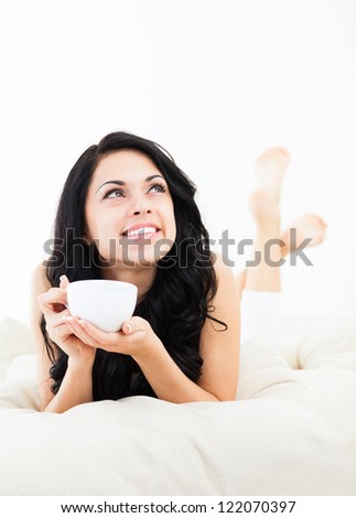 beautiful young woman hold cup of coffee lying think relaxing on the couch sofa home indoors happy smile day dreaming with tea mug in hands looking up away in thought beautiful young woman hold cup of coffee lying think relaxing on the couch sofa home indoors happy smile day dreaming with tea mug in hands looking up away in thought