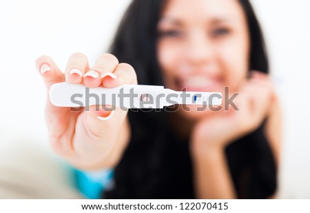 pregnancy test positive result smiling woman, young girl happy smile in bedroom, focus on foreground 2 stripes