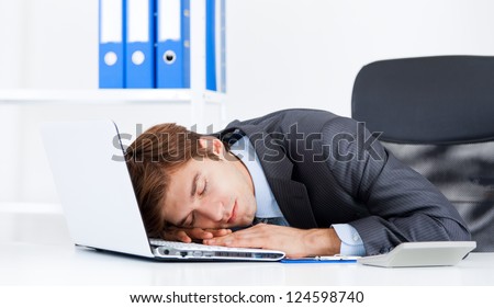 young business man sleeping on his laptop resting on workplace during work day, businessman relaxed sitting at office lying on desk with closed eyes, concept of workout, exhausted sleep, tired