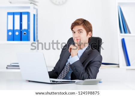 businessman with finger on lips smile sitting at the desk in office, handsome young business man, concept of silence, commercial financial secret
