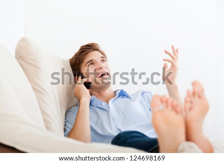 man phone call smile lying on sofa in living room, at home - indoors, excited guy talking cellphone sitting, relaxing on couch