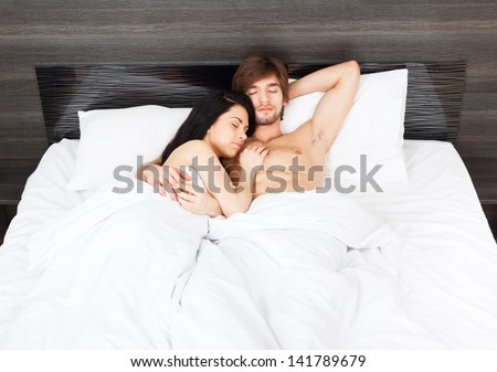 young couple sleep in bed, man embrace love woman, closed eyes lying in bedroom