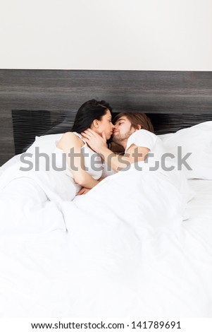 young couple kiss in bed, man embrace love woman, lying in bedroom, romantic valentine day concept