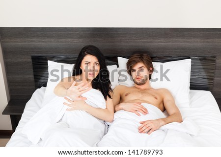 unhappy surprise couple lying in a bed, lovers caught in betrayal cheat, unfaithful man and woman afraid negative emotions concept