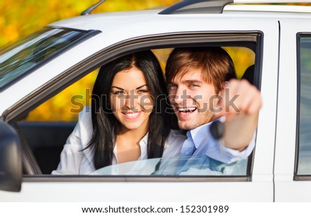 young happy couple driving, excited man and woman buy new car smile hold hand keys