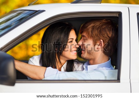 young smile couple romantic kissing sitting in car driving, fall season, golden autumn trees, yellow leaves background