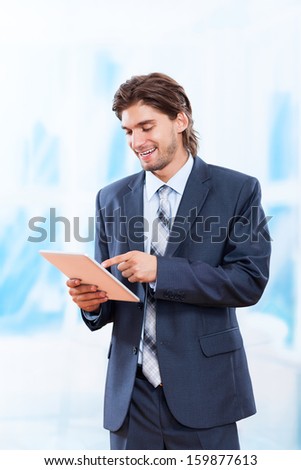 business man using tablet pad computer in bright blue office, touch screen young businessman