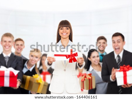 Business woman happy smile hold gift card present with red bow. Businesswoman over big group of people human resources background