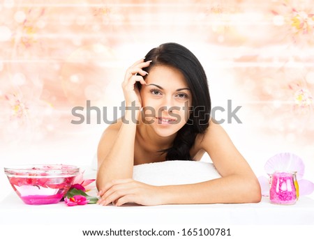 woman in spa salon lying on massage table, beauty girl smile, body health care over flower background