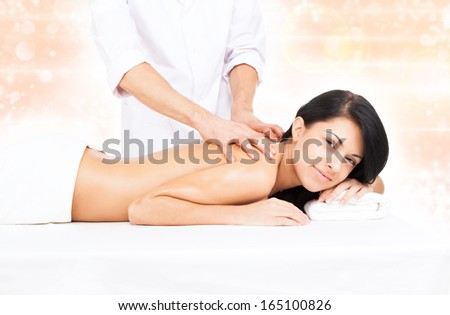 woman in spa salon lying on massage table, beauty girl smile messeur hands on back, body health care over flower background
