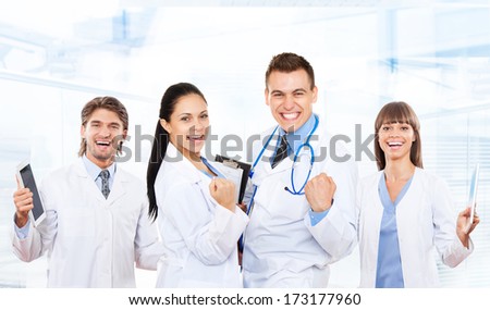 medical team doctor happy smile excited, hold fist yes hand gesture wear white coat with stethoscope, group of people celebrating in hospital