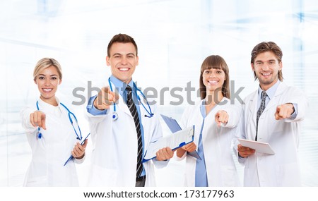 medical doctor team smile with stethoscope point finger at you. Excited happy smiling group of people in hospital, wear white lab coats