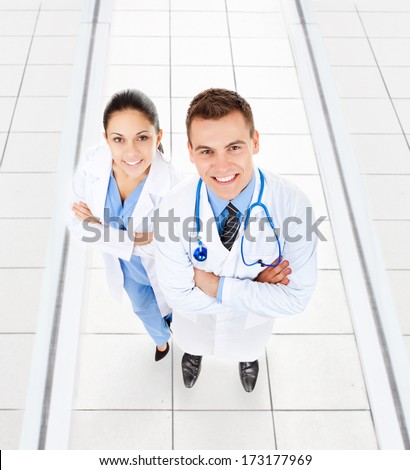 medical team doctor man and woman happy smile with stethoscope folded hands in hospital. Full length portrait top angle view