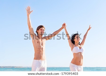 Happy couple on beach hold raised up arms, stretching hands, beautiful young happy man and woman smile, concept freedom summer ocean holiday travel