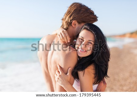 Couple embrace on beach, love laughing woman hug man happy smile sea shore romantic smiling, summer ocean vacation holiday travel