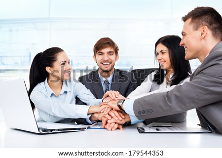 Business people collaboration team at office meeting, group smile businesspeople leader hold pile of hands putting on top of each other on desk, concept of colleagues working together cooperation