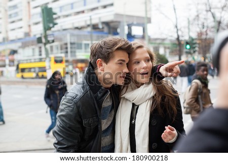 Young man showing something to woman on city street