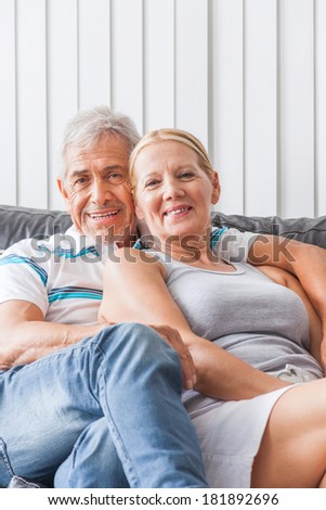 senior couple embrace sitting on sofa happy smile looking at camera, portrait of lovely mature old man and woman hug, on couch