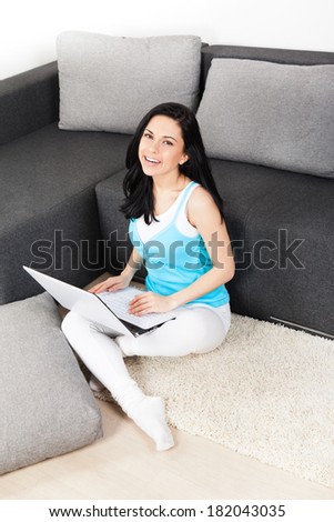 woman happy smile with laptop sitting on floor living room near sofa at home, young beautiful girl surfing on computer top angle above view