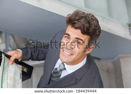 businessman face happy smile with newspaper modern office stairs, handsome business man, wear elegant gray suit top angle view