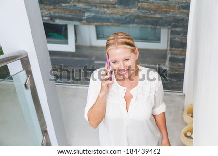 senior woman smile cell phone call talking, modern home stairs