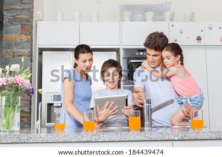 Family using a tablet pc in kitchen, parents with children happy smile, modern kitchen orange juice