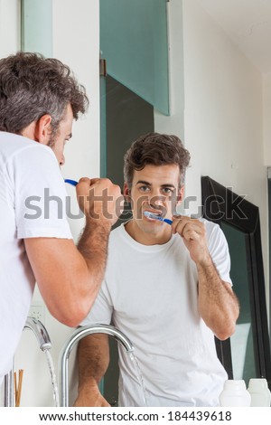 man brush teeth, morning bathroom at home, looking to mirror happy smile male brushing tooth paste