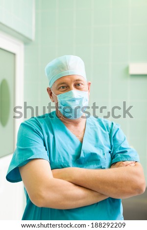 surgeon man relaxed smile confident in surgical room hospital, medical doctor wear green surgery scrub suit, mask and cap in operating