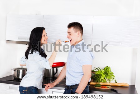 couple tasting the meal in their kitchen happy smile, woman feed man with spoon cooking at home